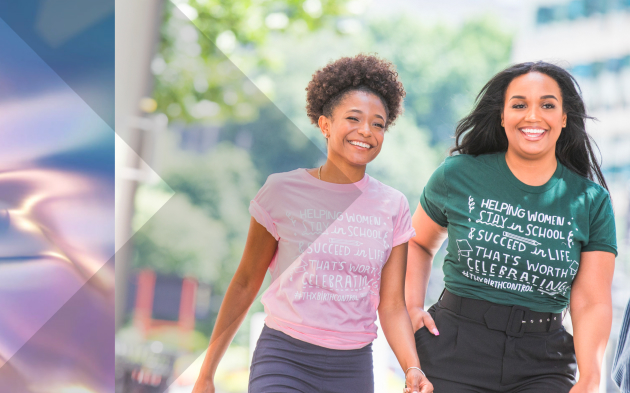 Two women walking in a tree-lined urban area.