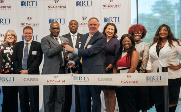 The RTI leadership team standing behind a symbolic ribbon to announce a project initiation.